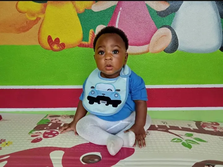 Bébé souriant assis devant une fresque colorée