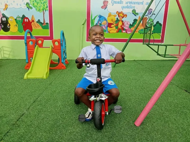 Un petit garçon en tricycle dans la cour de jeux du Berceau des Anges
